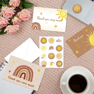 Bohemian thank you card set with rainbow designs, stickers and white envelope on a desk