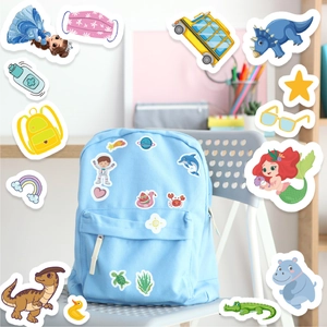 Detailed view of colorful cartoon stickers on a blue backpack featuring unicorn and dinosaur