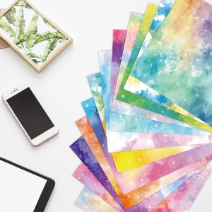 Papel artesanal degradado acuarela con patrones de galaxias en un escritorio blanco moderno