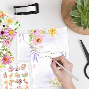 Watercolor floral stationery set with envelopes and stickers on a white desk