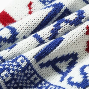 Macro shot of tricolor jacquard knit fabric showing Christmas deer and letter patterns