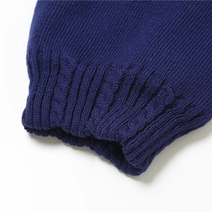Close-up of dark blue knit sleeve featuring detailed cable patterns and ribbed cuffs