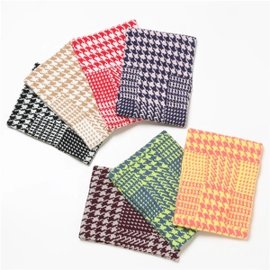 Detailed view of knitted neck warmers in various houndstooth patterns and soft colors