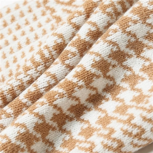 Macro view of soft knitted houndstooth fabric in camel and white with detailed textures
