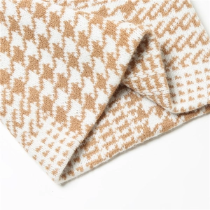Detail shot of soft camel and white houndstooth knit fabric texture and premium weaving