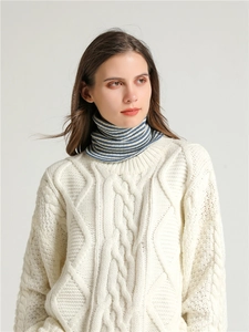 Close-up of a navy and cream striped knit neck warmer paired with a cable knit sweater