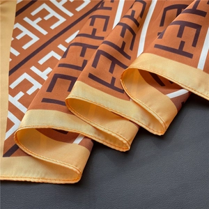 Close-up of silk-textured scarf with orange F-pattern on black leather background