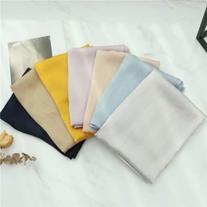 Detail of silk scarves in navy, khaki, and pastel tones with delicate ribbed texture