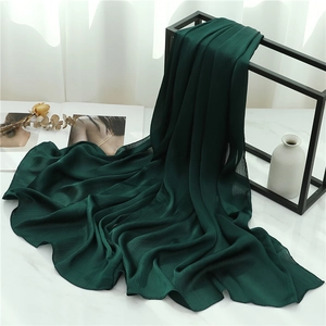 Detailed view of dark green pleated scarf texture draped over marble surface