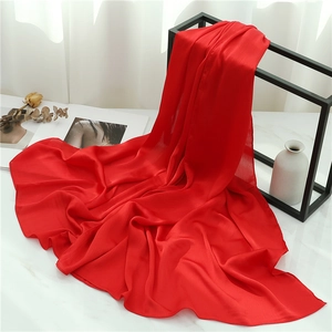 Detail of red crinkle scarf with elegant texture draped on a marble surface