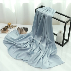 Detail view of a dusty blue crinkle scarf with fine pleated texture and soft draping