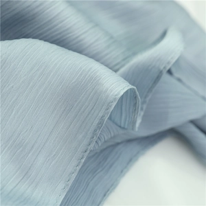 Macro view of light blue wrinkled fabric texture with delicate stitching details