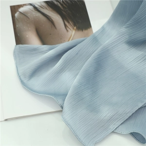 Macro shot of light blue pleated scarf fabric with fine vertical accordion texture