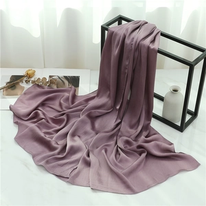 Detail of mauve pleated scarf draped on a rack with elegant vertical texture and silk sheen