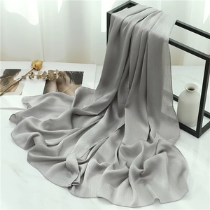 Detail of pleated grey chiffon scarf hanging on a black stand with minimalist decor