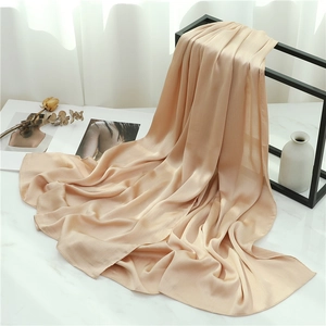 Detail view of champagne gold pleated scarf with elegant texture on a minimalist stand