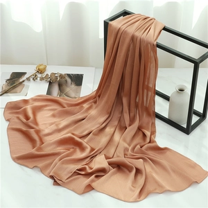Detail of terracotta pleated scarf with vertical crushed texture on a minimalist display