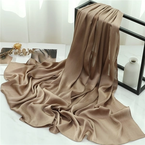 Detailed view of camel pleated shawl scarf draped elegantly on a modern minimalist metal rack