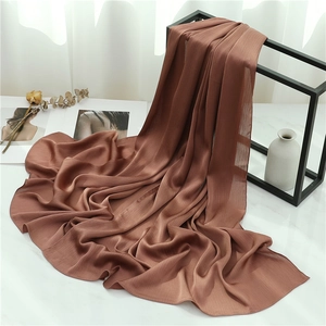 Detail of dark brown crinkle shawl draped elegantly over a minimalist metal stand
