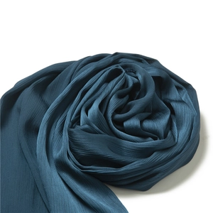 Detailed view of dark peacock blue pleated fabric scarf with soft rippled texture