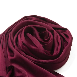Macro view of burgundy pleated scarf showing vertical texture and silky matte fabric