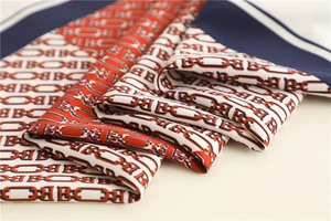 Detail of silk-like chain print scarf showing navy and red twill texture and hem
