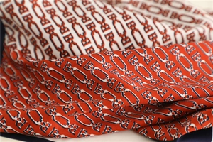 Close-up of red and navy chain print silk scarf showing detailed twill weave texture