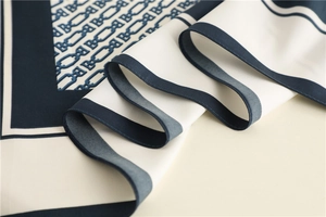 Close-up of chain pattern and B-letter print on luxury silk scarf with navy trim