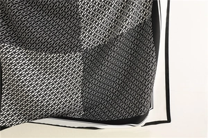 Macro detail of silk scarf showing black and white geometric chain pattern and soft texture