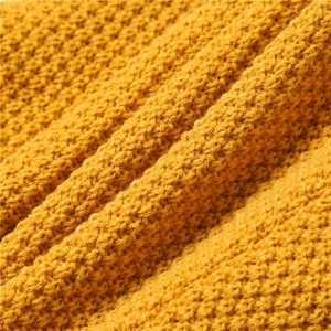 Detailed macro view of the ginger yellow thick knit fabric with waffle texture and soft yarn