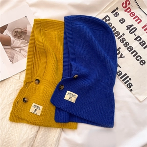 Dettaglio del passamontagna in maglia con bottoni nei colori giallo zenzero e blu cobalto
