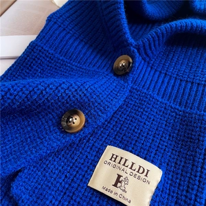 Dettaglio passamontagna blu in maglia grossa con bottoni marmorizzati e etichetta