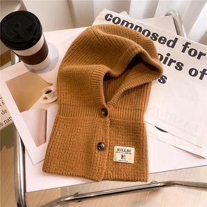 Sciarpa con cappuccio in maglia caramello con bottoni su un vassoio decorativo