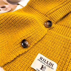Dettaglio ravvicinato della trama in maglia zenzero con bottoni e etichetta brand
