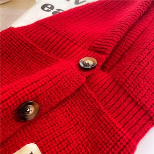 Dettaglio in maglia grossa rossa con bottoni decorativi in tartaruga scura