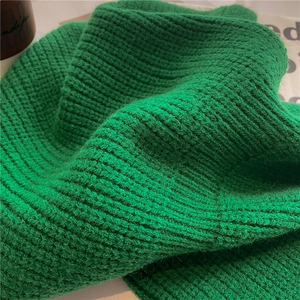 Primo piano di sciarpa in maglia verde smeraldo con trama spessa e tessuto morbido