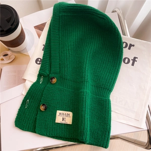 Dettaglio del passamontagna in maglia verde smeraldo con trama intrecciata e bottoni