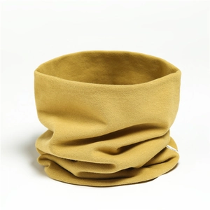 Detailed close-up of mustard yellow knitted neck warmer with white brand label on white background