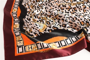 Detail of leopard print silk scarf with golden chain patterns and wine red border