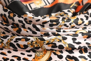 Close-up of luxury silk scarf with leopard print and golden chain design details