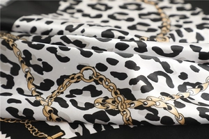 Close-up of leopard print satin scarf featuring golden chain patterns and silky texture