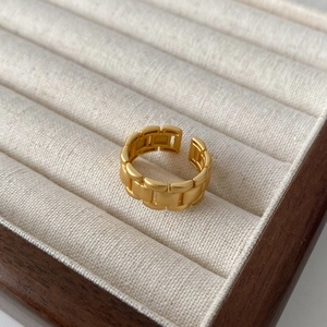 Close-up of gold-plated chain link ring with matte finish on a velvet jewelry display