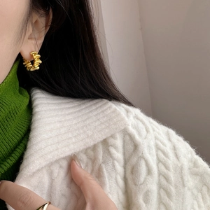 Close-up of matte gold vintage earrings with irregular pleated texture on a model