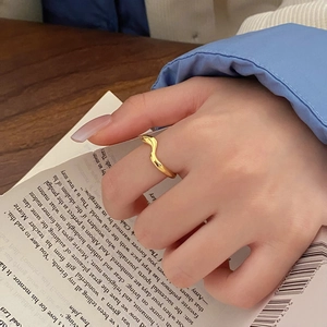 Minimalist double-layered gold wavy ring for women with polished finish on a book background
