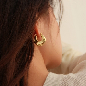 French vintage style chunky gold-plated hoop earrings worn by a model in soft light