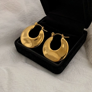 Detailed macro view of gold-plated crescent hoop earrings resting in a black velvet jewelry box
