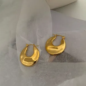 Macro detail of polished gold-plated hoop earrings on artistic white tissue paper