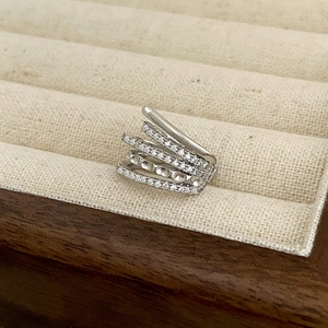 Detail of multi-layer silver ring with cubic zirconia stones in a beige velvet jewelry box