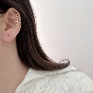 Cross zircon ear cuff in gold finish with sparkling pear-shaped stones on model