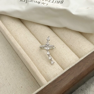 Macro shot of silver zircon ear cuff with cross design on a beige linen jewelry box